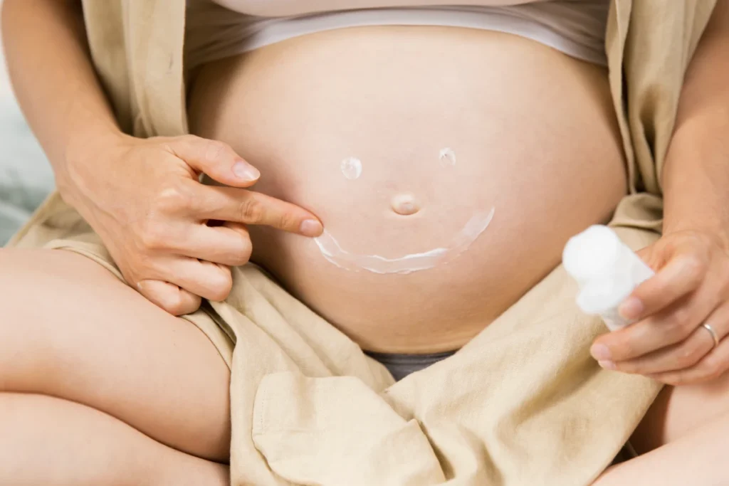 Mujer embarazada aplicándose crema hidratante en el abdomen como parte del cuidado de la piel