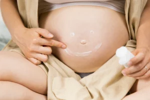 Mujer embarazada aplicándose crema hidratante en el abdomen como parte del cuidado de la piel